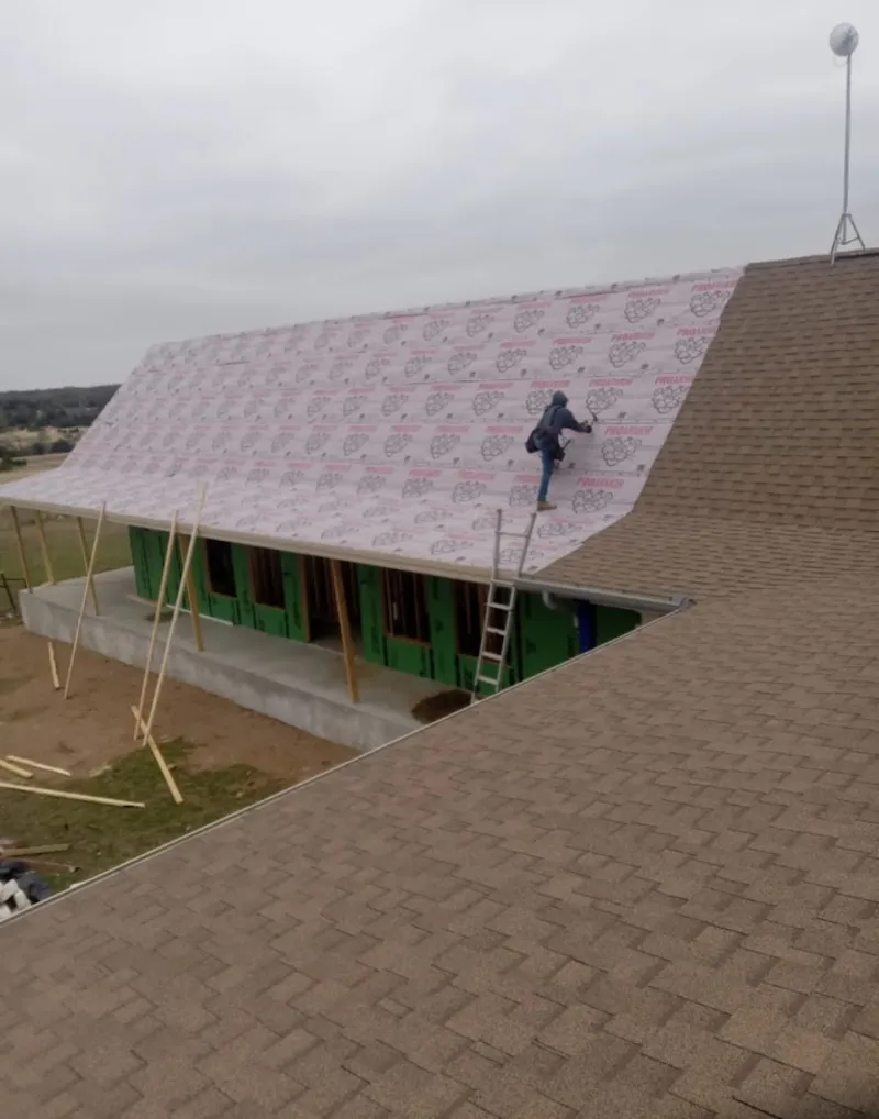 Worker preparing underlayment for a metal roof installation in Shrewsbury